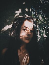 Portrait of woman by plants in sunny day