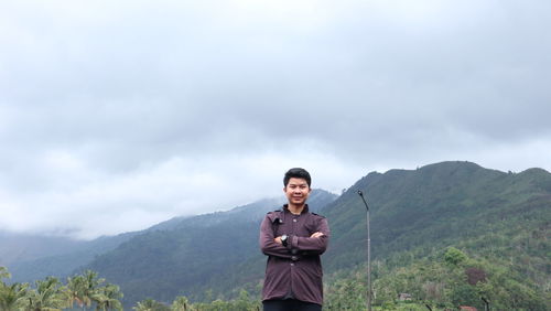 Portrait of man standing on mountain against sky