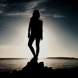 Silhouette man standing by sea against sky during sunset