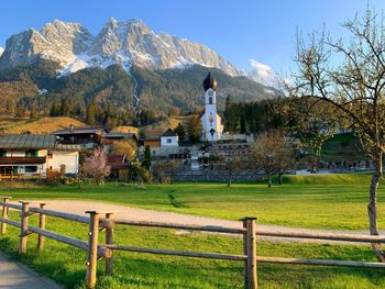 Houses standing on field by buildings against sky