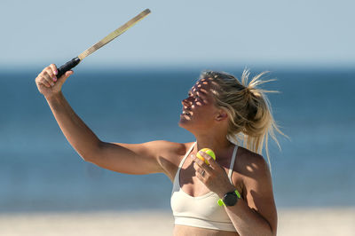 Young woman playing tennis on beach