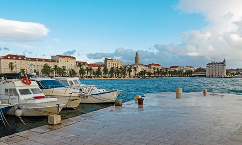 Boats moored at harbor against buildings in city