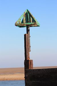 Low angle view of wooden post on sea against clear sky