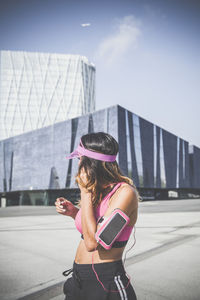 Woman with umbrella in city against sky