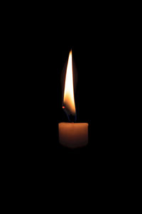 Close-up of lit candle in darkroom