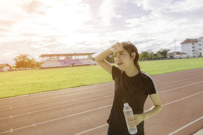 Female athlete holding water bottle on running track