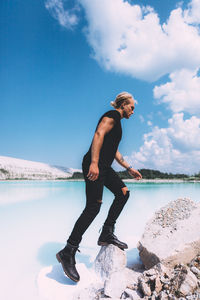 Side view of young man in lake against sky