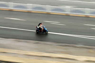 High view of woman riding motorcycle on road in city 