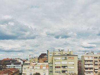 Buildings in city against cloudy sky