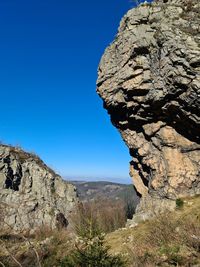 Rock formations on landscape against clear blue sky