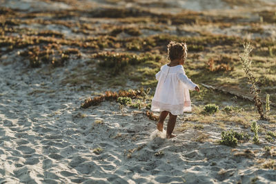 Behind view of little girl running away at beach