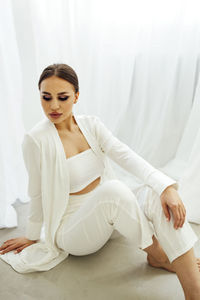 Portrait of young woman sitting on bed at home