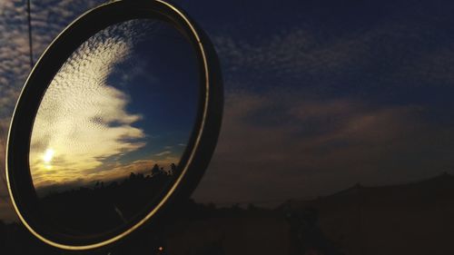 Close-up of sunglasses against sky during sunset