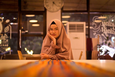 Portrait of young woman sitting on table