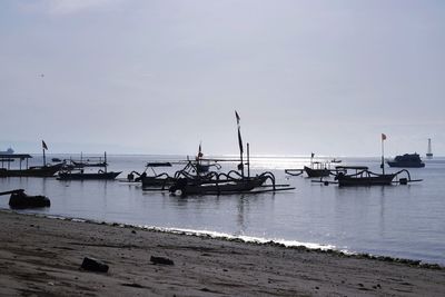 Sailboats moored on sea against sky