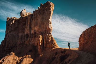 Man standing on rock by mountain against sky