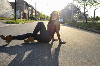 Full length portrait of young woman on road in city