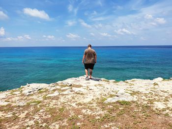 Rear view of man looking at sea against sky