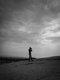 Side view of man standing on field against sky