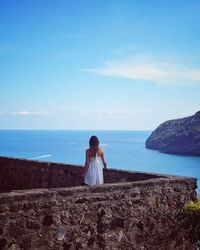 Rear view of woman standing by sea