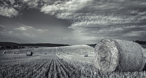 Hay bales on field against sky