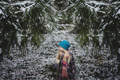 Girl with stuffed toy standing at backyard during winter