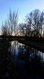Silhouette trees by lake against sky during sunset