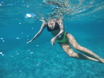 Low section of woman swimming undersea