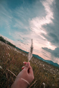 Person holding umbrella on field against sky