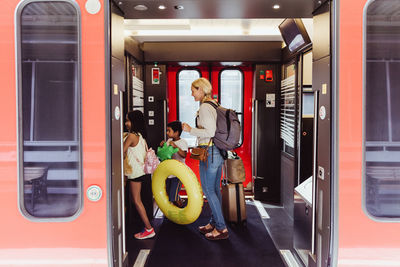 Mother and children with luggage walking in train at station