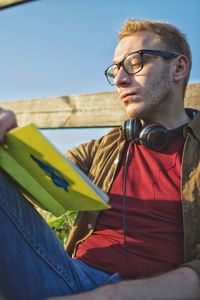 Young man looking away while sitting outdoors