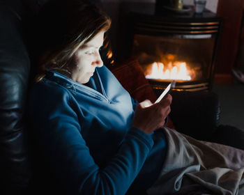 High angle view of woman using smart phone while sitting on sofa at home