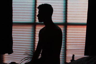 Silhouette man kneeling on bed at home