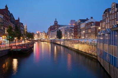 Boat anchored on canal amidst buildings