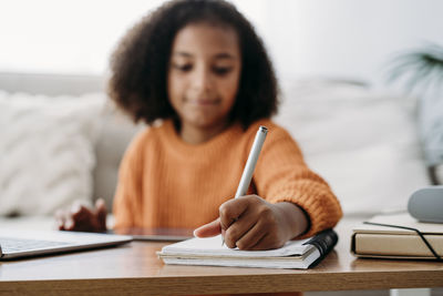 Girl with pen and notepad doing homework at home