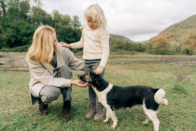 Mom and daughter walk the dog in the countryside.