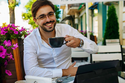 Portrait of young man using mobile phone while sitting in cafe