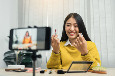 Young woman using mobile phone while sitting on table