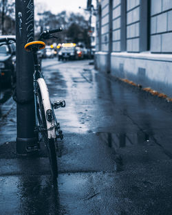 Bicycle parked on wet street in city