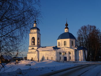 Church by building against clear sky during winter