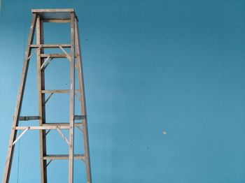 Close-up of ladder against blue wall