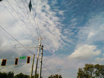 Low angle view of electricity pylon against cloudy sky