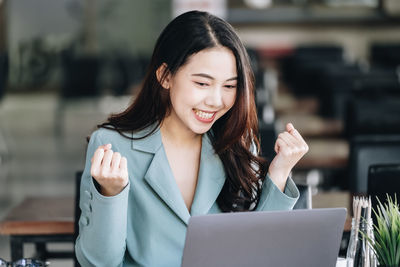 Young businesswoman using laptop while sitting on table