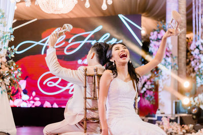 Portrait of happy young woman with arms raised