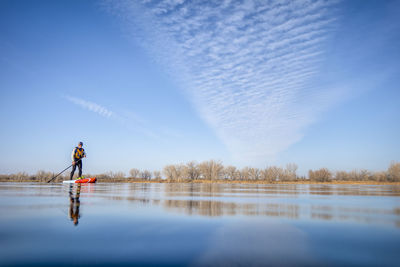 Man standing on lake against sky
