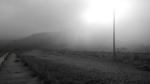 Road passing through field in foggy weather