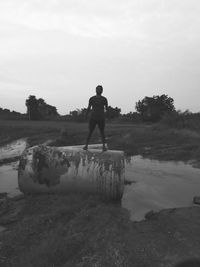 Rear view of man standing on field against sky