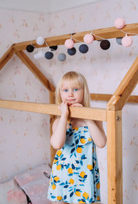 Little cute girl child blonde at home in her wooden bed house