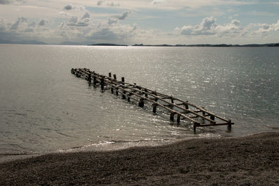 Wooden posts in sea against sky