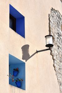 Low angle view of lamp mounted on wall of building